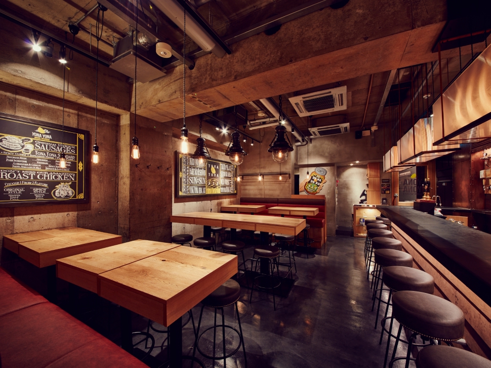 Interior with exposed concrete walls and wooden tables at YONA YONA BEER WORKS Aoyama Branch