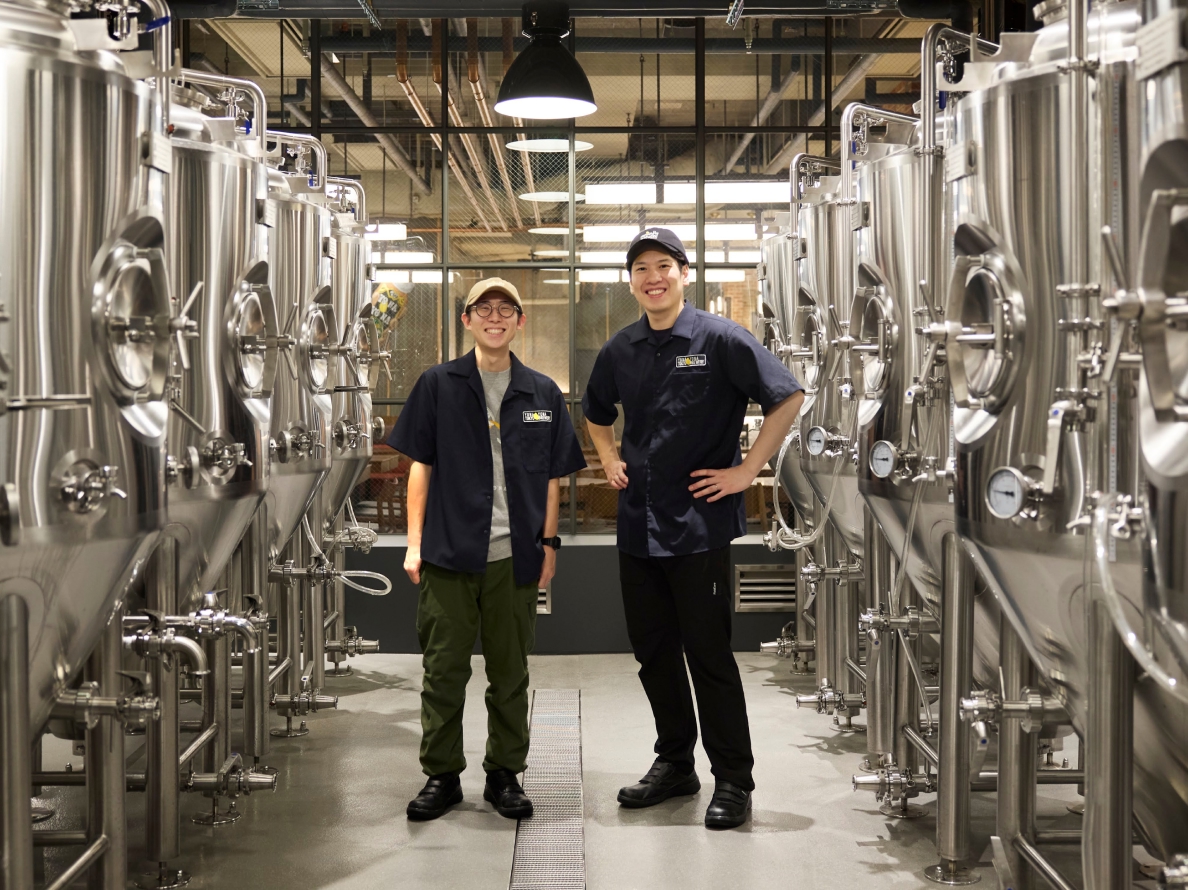 Brewing corridor with tanks on both sides and two smiling brewers