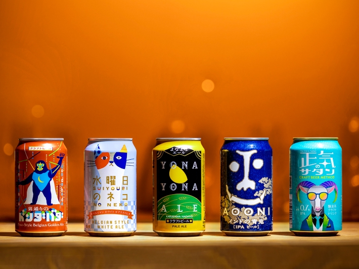 A product photo showing five types of cans lined up from left to right: 'DONDABADA', 'Wednesday Cat', 'YONA YONA ALE', 'Aooni IPA', and 'SINLESS SATAN'